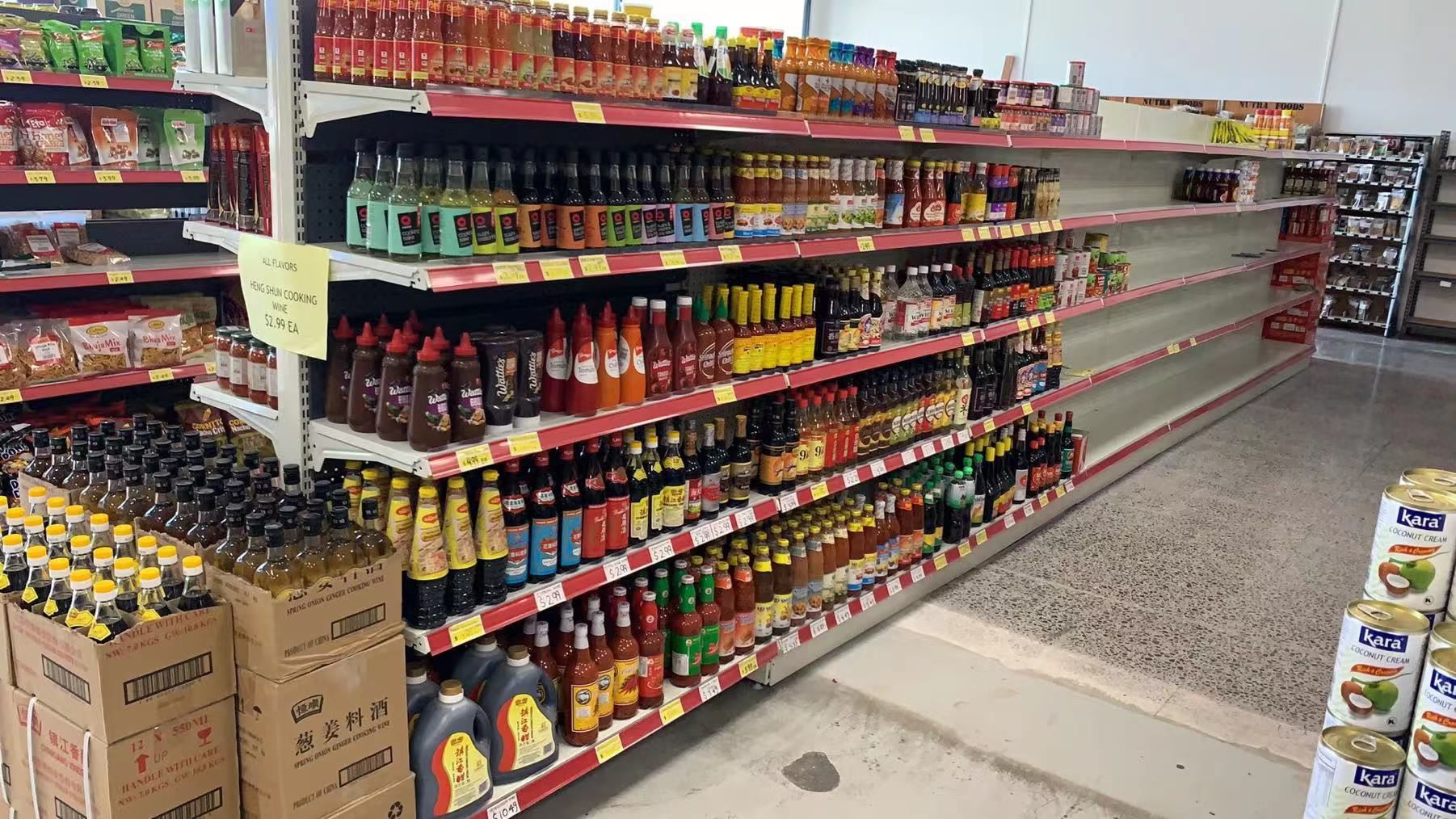 Asian grocery store aisle with soy sauce, chili sauce, and cooking condiments on shelves at Kiwi Choice New Zealand